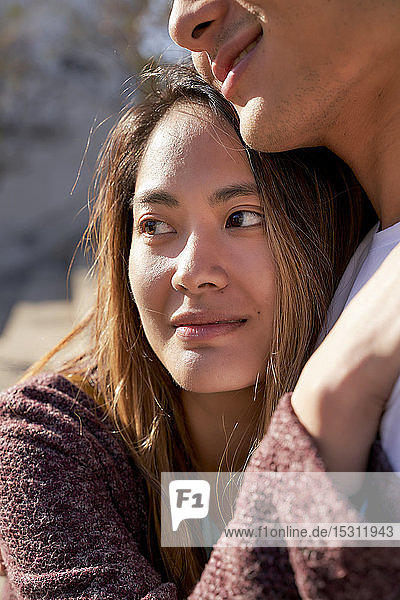 Happy young woman hugging boyfriend outdoors