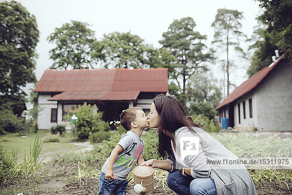 Mutter und Kleinkind küssen sich im Garten