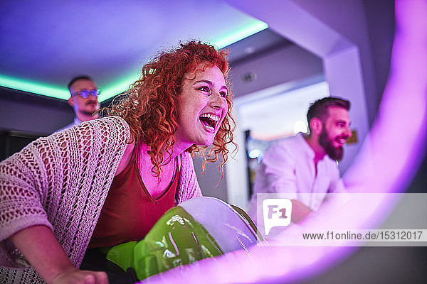 Frau spielt und vergnügt sich mit einem Fahrsimulator in einer Spielhalle