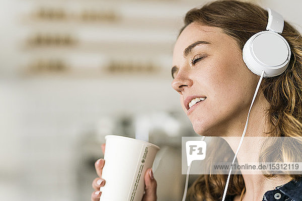 Junge Frau im Café  die mit Kopfhörern Musik hört