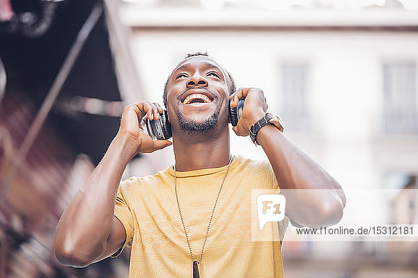 Portrait of happy man listening music with headphones looking up