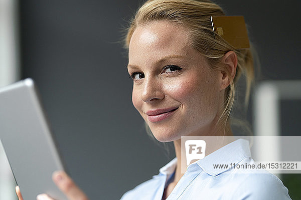 Porträt einer lächelnden jungen Frau mit Tablette und Kreditkarte