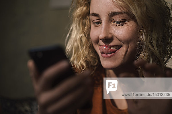 Porträt einer blonden jungen Frau  die ihr Handy für einen Video-Chat benutzt