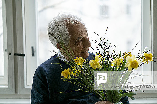 Älterer Mann mit Blumenstrauss zu Hause