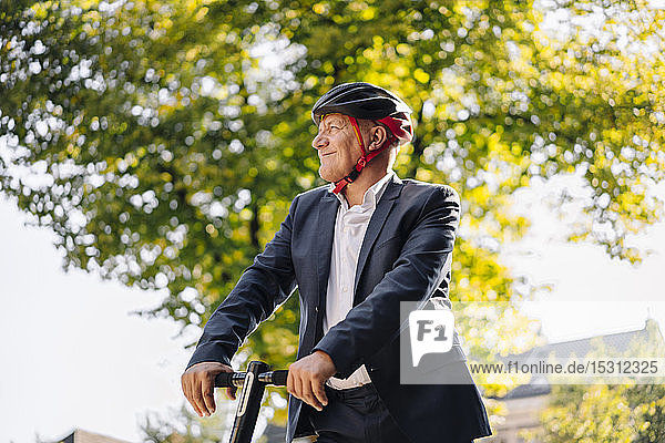 Portrait of smiling senior man with e-scooter in the city