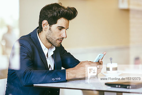 Businessman using smartphone in an urban cafe