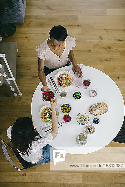 Zwei Frauen sitzen am Tisch und nehmen eine gesunde Mahlzeit ein