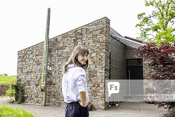 Lächelnde Frau steht vor einem Haus