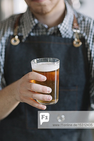 Nahaufnahme eines jungen Mannes mit Bierglas in der Hand in einer Brauerei