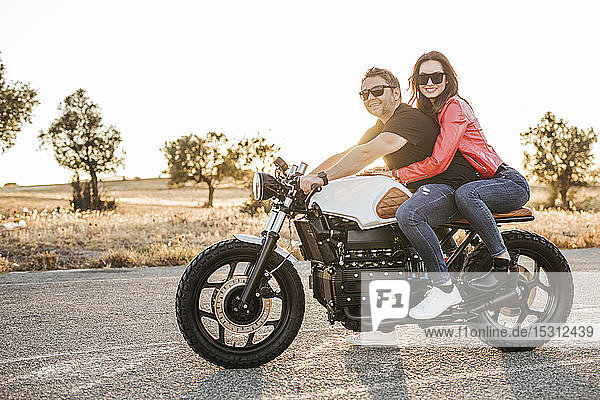 Portrait of couple sitting on motorbike at evening twilight