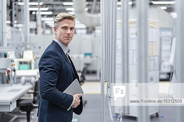 Confident businessman with tablet in a modern factory