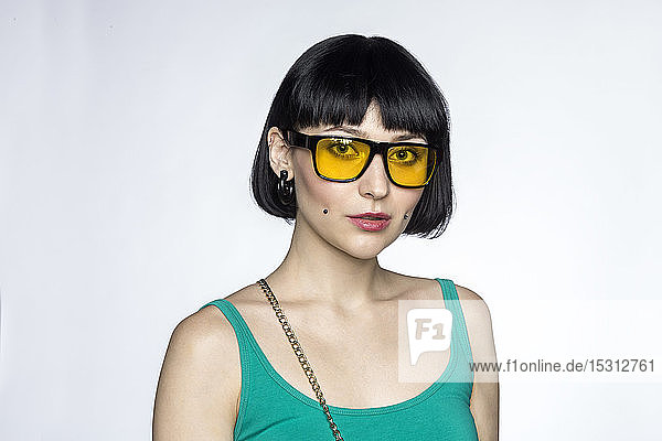 Porträt einer jungen Frau mit Wangenpiercing und gelber Brille
