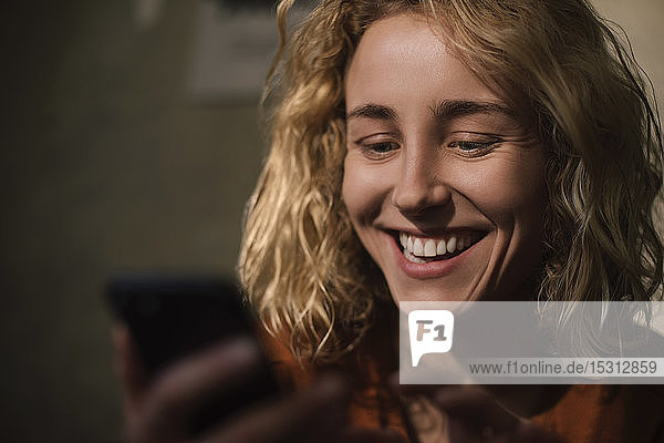 Porträt einer blonden jungen Frau bei der Benutzung eines Mobiltelefons