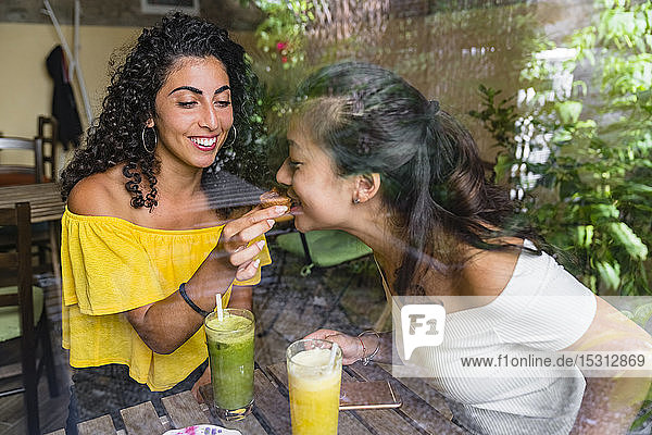 Lächelnde junge Frau in einem Café  die mit ihrem Freund einen Keks teilt