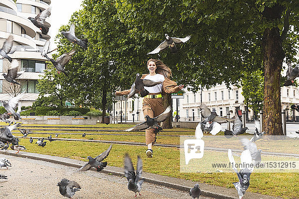 Sorglose junge Frau  die Spaß im Park hat und Tauben jagt  London  UK