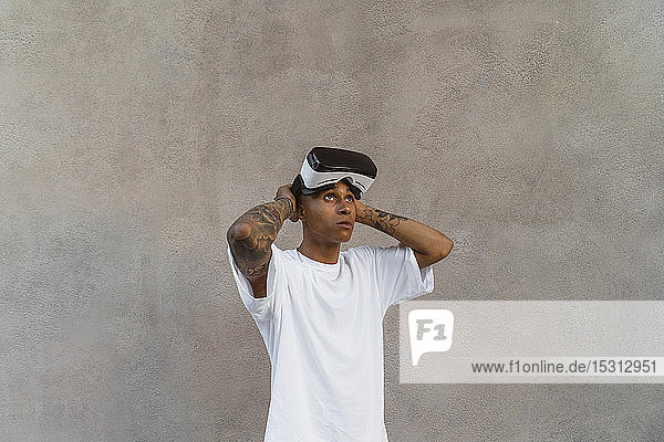 Tattooed young man with Virtual Reality Glasses looking up