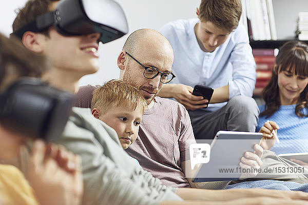 Happy family sitting on couch  using VR goggles and mobile devices