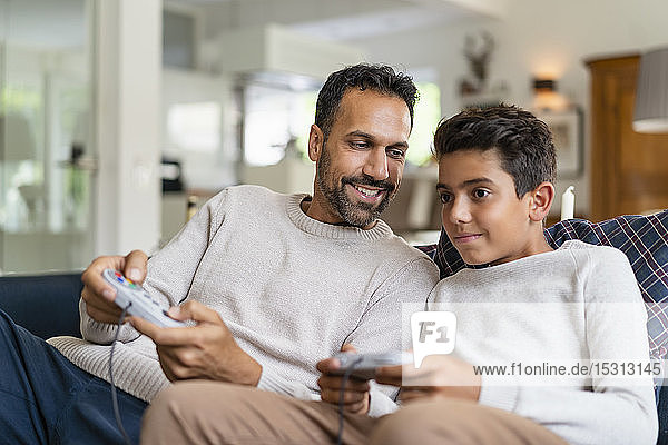 Glücklicher Vater und Sohn spielen Videospiel auf der Couch im Wohnzimmer