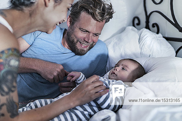 Happy parents with their baby in bed