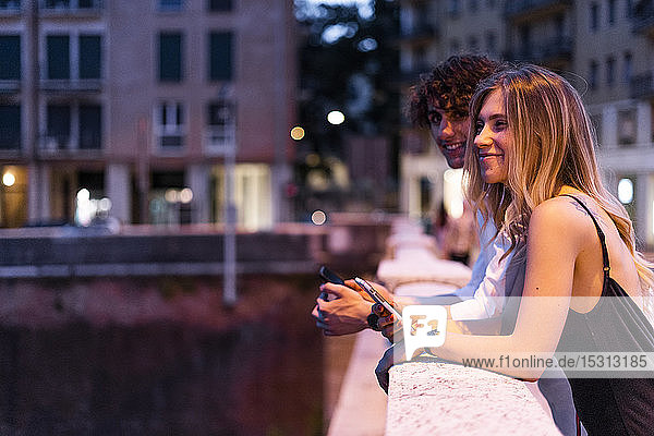 Glückliches junges Paar lehnt nachts am Brückengeländer  Verona  Italien