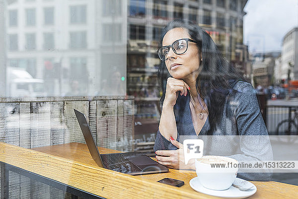 Geschäftsfrau  die in einem Café eine Pause macht und mit einem Laptop arbeitet