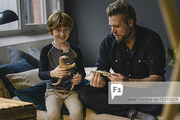 Portrait boy sitting with his father on couch kneading dinosaur