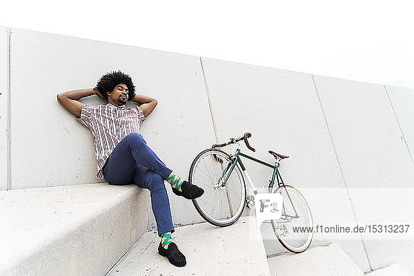 Young man during break leaning on a wall  bicycle