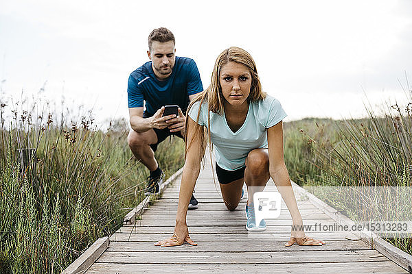 Female jogger with her coach on a wooden walkway