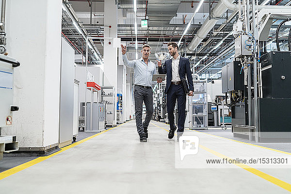 Two businessmen with tablet talking in a modern factory