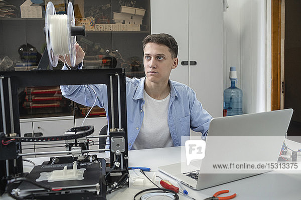 Student setting up 3D printer  using laptop