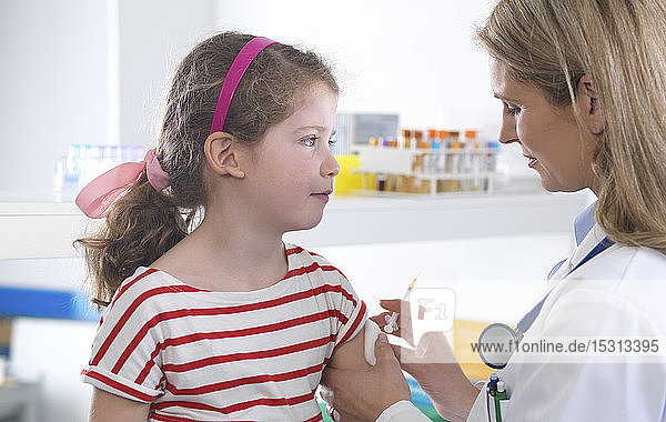Ärztin gibt einem jungen Mädchen in der Klinik eine Routineimpfung