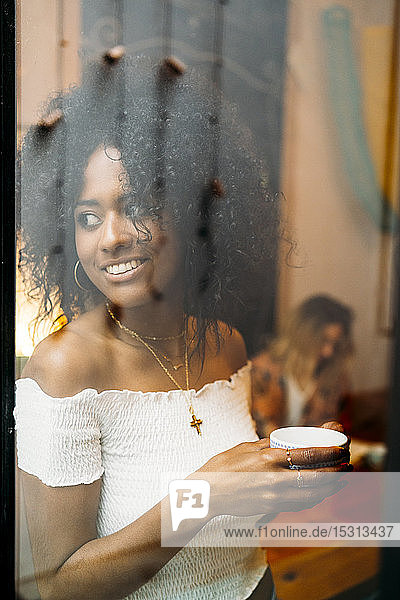 Frau mit einer Tasse Kaffee  die aus dem Fenster schaut  in einem Cafe