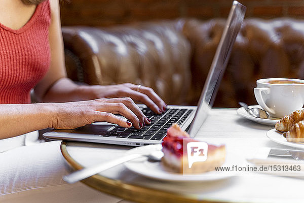 Junge Bloggerin arbeitet am Laptop in einem Café  Teilansicht