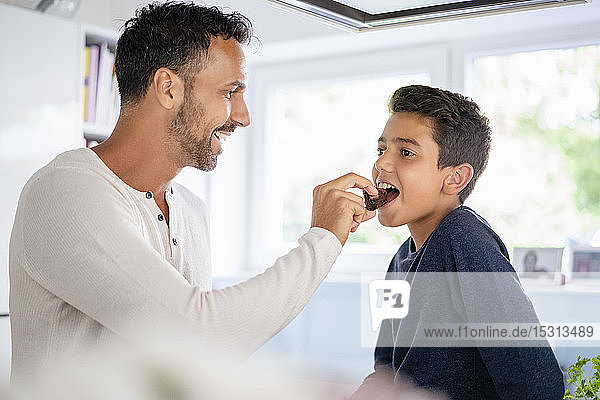 Happy father feeding son in kitchen