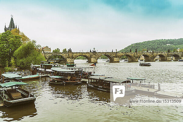 Blick auf die Karlsbrücke mit vertäuten Ausflugsbooten im Vordergrund  Prag  Tschechische Republik