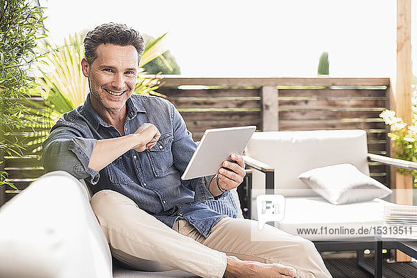 Mature man sitting on terrace using digital tablet
