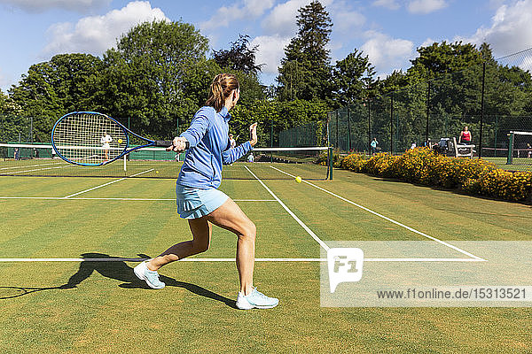 Reife Frau während eines Tennisspiels auf Rasen