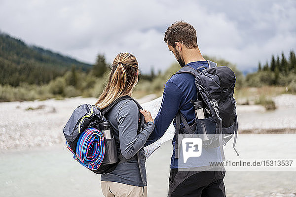 Young couple on a hiking trip reading map  Vorderriss  Bavaria  Germany