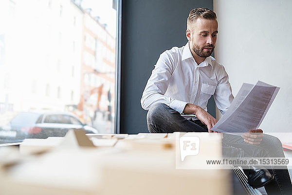 Businessman with papers and architectural model in office