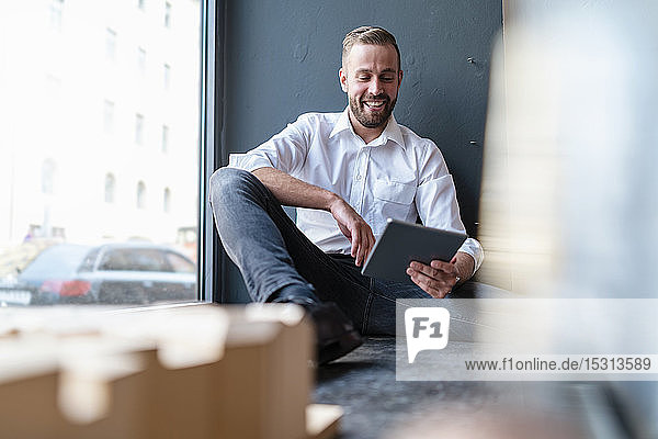 Happy businessman with tablet and architectural model in office