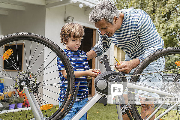 Father and son repairing a bicycle in garden