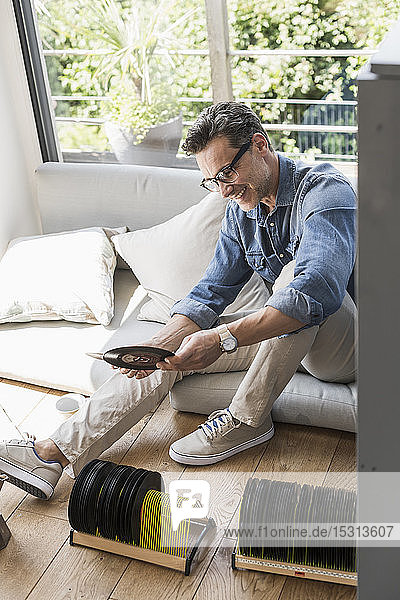 Mature man sitting at home looking at vintage sigle recors