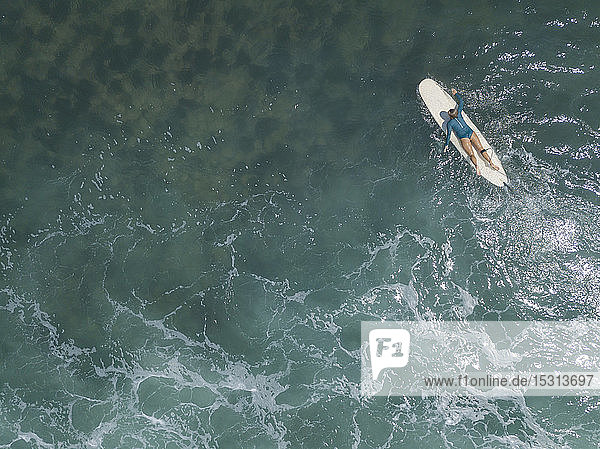 Luftaufnahme einer auf einem Surfbrett liegenden Surferin