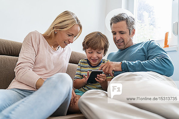 Father  mother and son using cell phone on couch at home