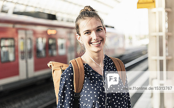 Porträt einer lächelnden jungen Frau am Bahnhof