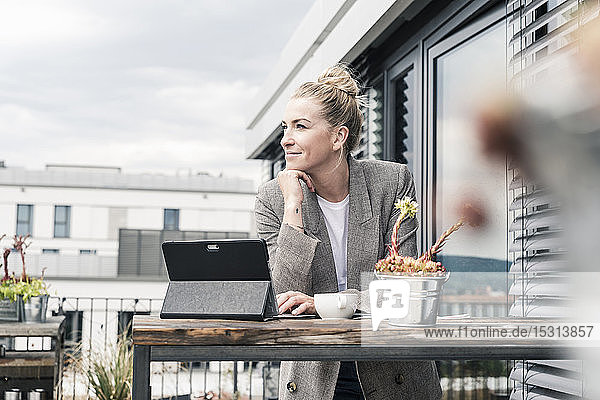 Businesswoman with tablet on roof terrace having a break