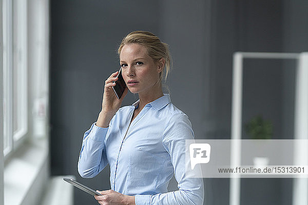 Junge Geschäftsfrau telefoniert im Büro per Handy