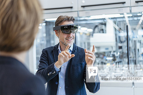 Businessman with AR glasses and businesswoman in a modern factory