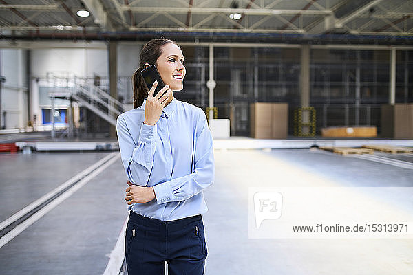 Smiling businesswoman on cell phone in a factory