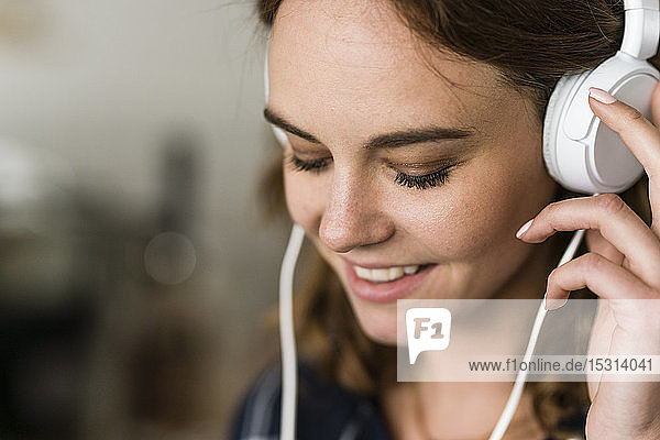 Junge Frau im Café  die mit Kopfhörern Musik hört
